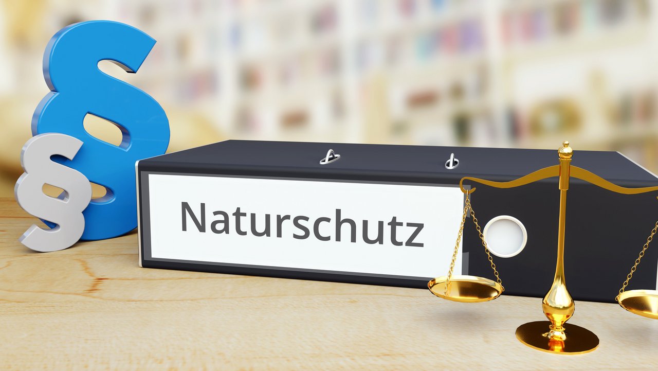 Das Foto zeigt einen Ordner mit der Aufschrift "Naturschutz". Links sieht man 2 Paragrafensymbole und rechts eine Waage
