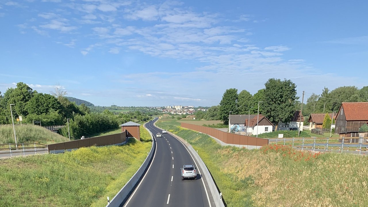 Blick auf die B 28 zwischen Rottenburg und Tübingen in Fahrtrichtung Rottenburg; rechts stehen drei Gebäude und im Hintergrund sieht man Rottenburg