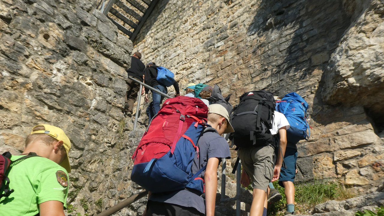 Das Foto zeigt Junior-Ranger, die mit Rucksäcken im Großen Lautertal unterwegs sind. 