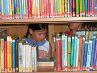 Mädchen hinter Bücherregal in der Schulbücherei Wolpertswende-Mochenwangen