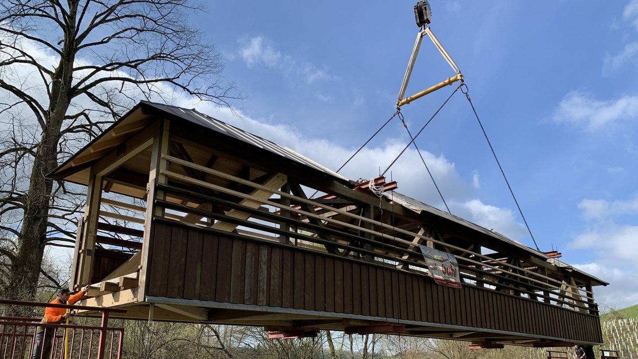 Ein sanierter Fachwerk-Brückenüberbau wird mit einem Autokran auf Widerlager versetzt