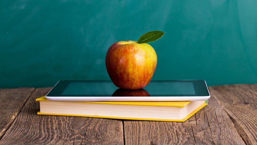 Ein Laptop, ein Buch und ein Apfel