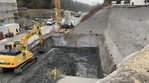 Eine Baugrube, die teilweise in einen Hang eingeschnitten ist. Die oberen Teile der Grube sind mit Beton gegen Abrutschen gesichert. 