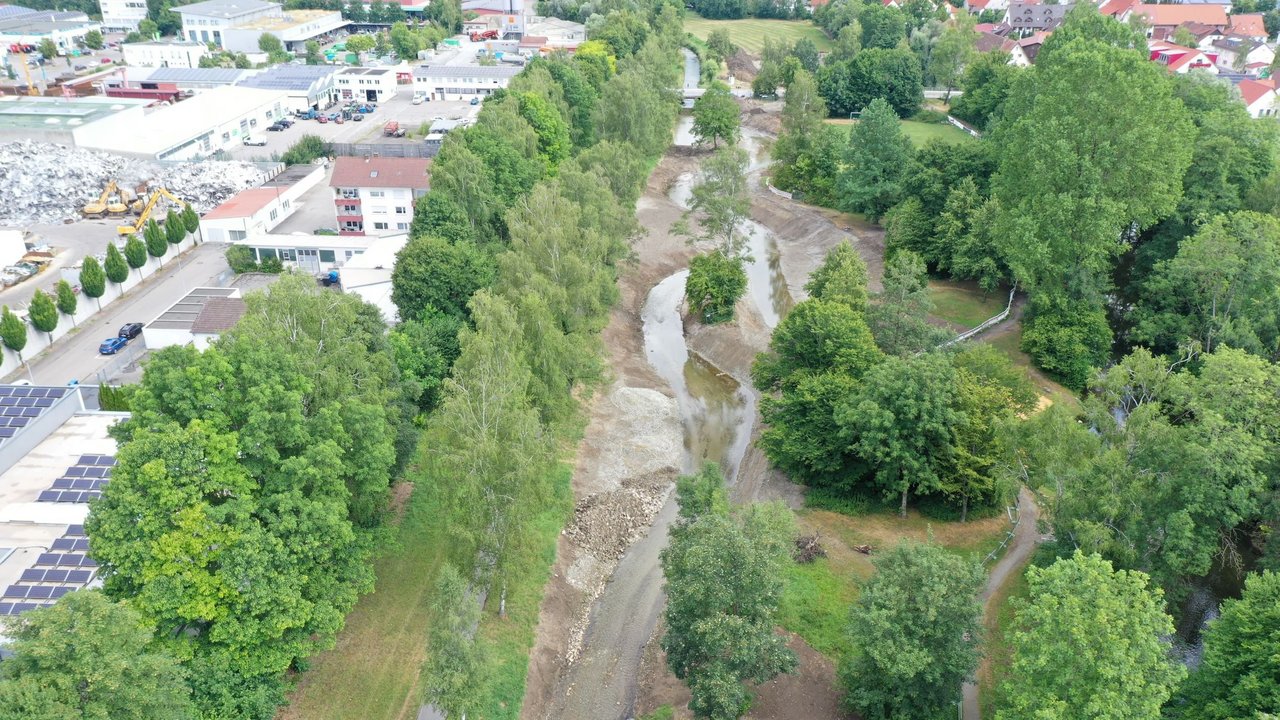 Das Bild zeigt einen revitalisierter Abschnitt der Riss bei Biberach; Bäume und Sträucher und Gebäude links