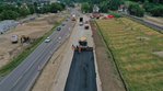 Eine Straße wird parallel zu einer bestehenden Straße asphaltiert.