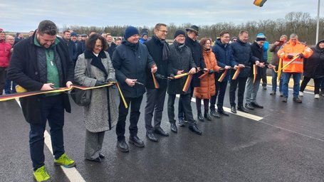 Banddurchschneidung am 20.12.24 Mehrere Personen durchschneiden ein Band. Das Band ist in den Farben der Deutschland-Flagge gestreift.