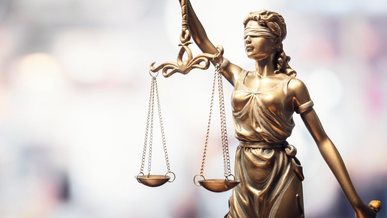 Statue Justitia Das Foto zeigt eine Statue aus Bronce mit verbundenen Augen und einer Waage in den Händen