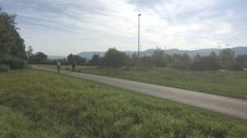 Ein Feldweg, im Hintergrund ist die Flutlichtanlage eines Sportplatz' zu sehen