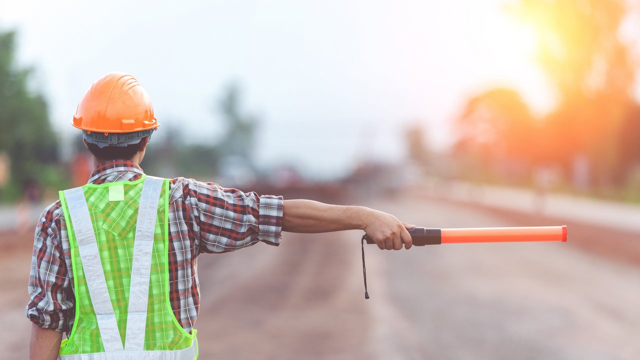 Das Foto zeigt einen Straßenwärter der nach rechts zeigt