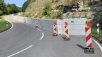 Das Foto zeigt die Hülbener Steige. Eine Wand aus Betonbauteilen sichert den rechten Streifen der Fahrbahn vor Felsstücken die vom Hang rutschen könnten. Mehrere Stehlen vor der Wand.