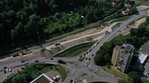 Luftbild einer Kreuzung neben einem Fluss. Neben der Straße laufen Bauarbeiten