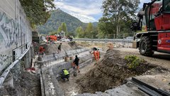 Bauarbeiten an einer Brücke. Der Überbau ist abgerissen, mehrere Arbeiter sind an den Widerlagern der Brücke zugange.