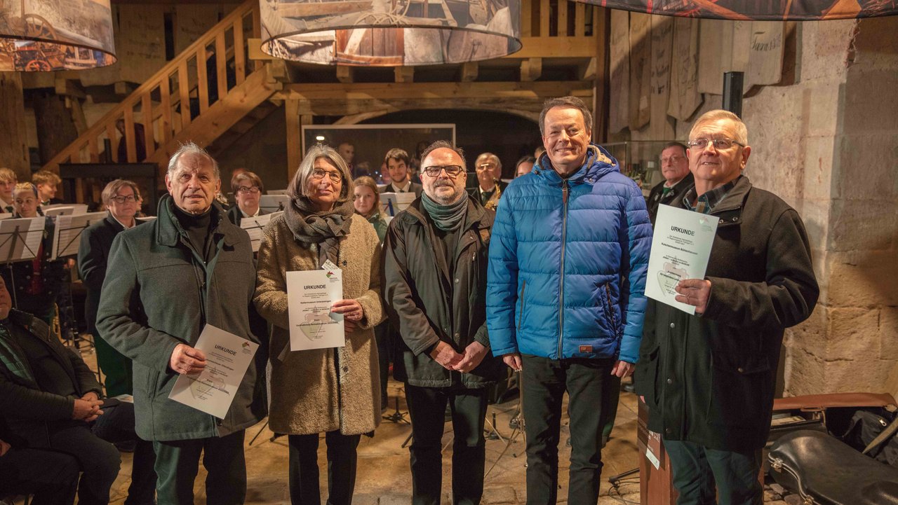 Preisverleihung vorbildliches Dorfmuseum: Fünf Menschen stehen in einer Reihe und lächeln in die Kamera.