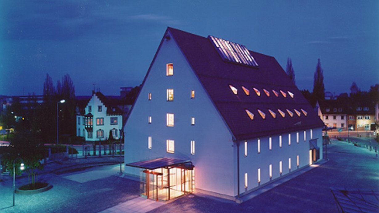 Stadtbücherei Biberach - beleuchtetes Gebäude auf dem Viehmarktplatz bei Nacht