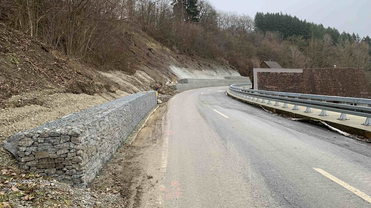 Straße in Hanglage mit Gabionenwand links