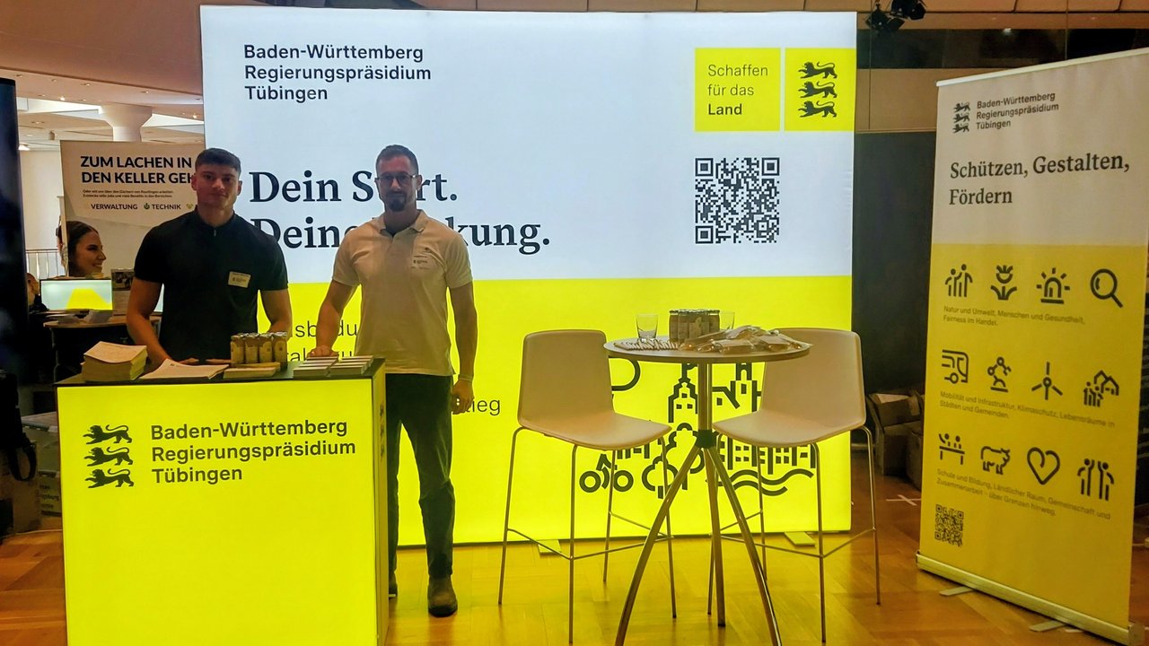 zwei Kollegen, Bastian Weinstein und Frederik Korbel stehen vor dem Messestand.