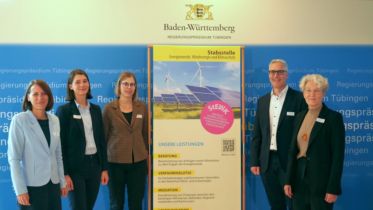 4 Frauen und ein Mann neben dem Plakat der Stabsstelle Energiewende, Windenergie und Klimaschutz