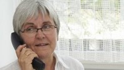 Eine Frau hält ein Telefonhörer ans Ohr