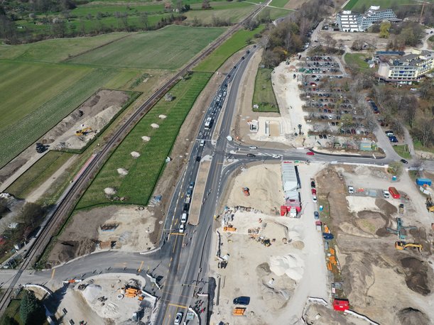 Luftbild einer Straßenbaustelle. Der Verkehr läuft auf einem Teil der vier Spuren, während auf beiden Seiten der Straße noch Bau-Aktivität herrscht.
