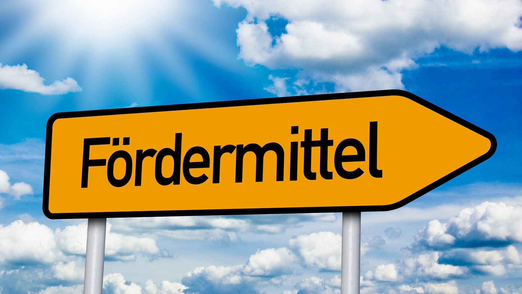 Gelber Pfeil. Schwarze Schrift Fördermittel. Bildhintergrund blauer Himmel mit weißen Wolken.