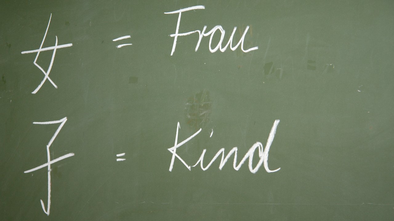 Chinesische Schriftzeichen Chinesische Schriftzeichen für Frau und Kind auf einer Tafel