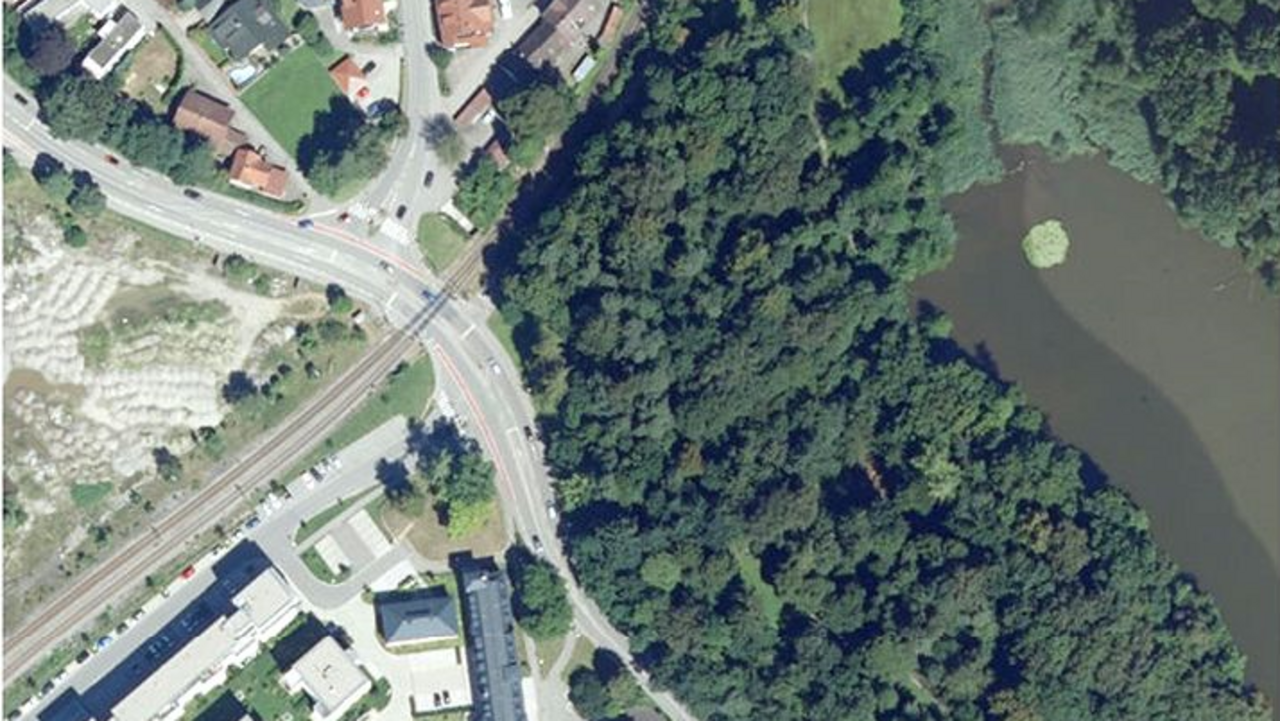 Luftbild; man sieht den Bahnübergang in Wangen, verschiedene Gebäude und ein Gewässer umrahmt von Bäumen