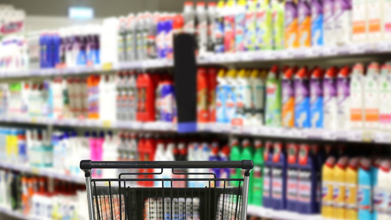 Das Bild zeigt eine Auswahl von Reinigungsmitteln und Toilettenpapier im Supermarkt und einen leeren Einkaufswagen
