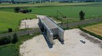 Eine Brücke über eine Bahnstrecke. Die Brücke steht als Beton-Bauwerk isoliert und hat noch keinen Anschluss an eine Straße.