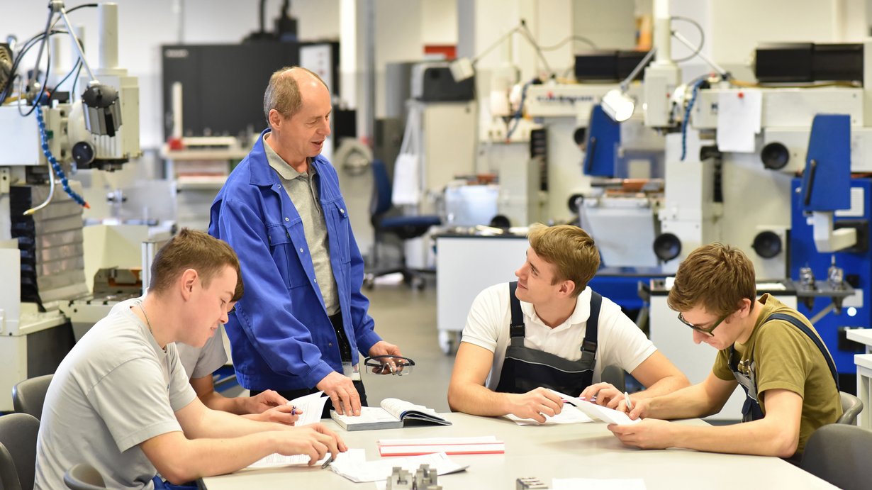 Gruppe von Jugendlichen in der technischen Berufsausbildung mit Lehrer in einer Lehrwerkstatt