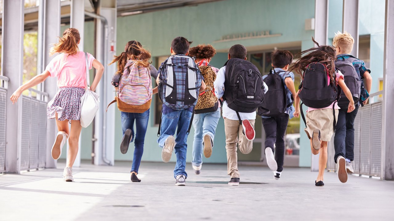 Gruppe von Grundschulkindern, die in die Schule laufen, Rückansicht