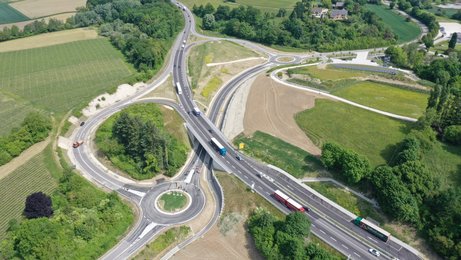 20. Mai 2025: Die fertige Maßnahme kurz vor der Öffnung für den Verkehr. Luftbild einer Straße, die von links oben nach rechts unten verläuft. In der Mitte der Straße ist eine Brücke, unter der ein Kreisverkehr liegt.