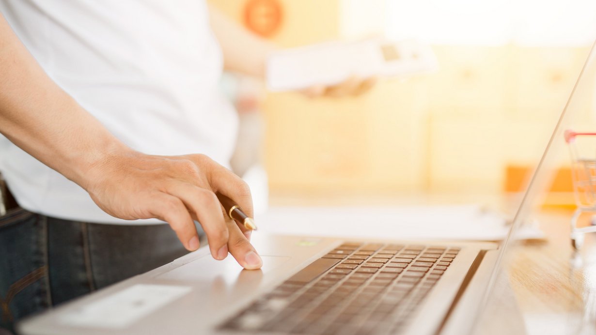 Mann betätigt Tastatur auf einem Laptop