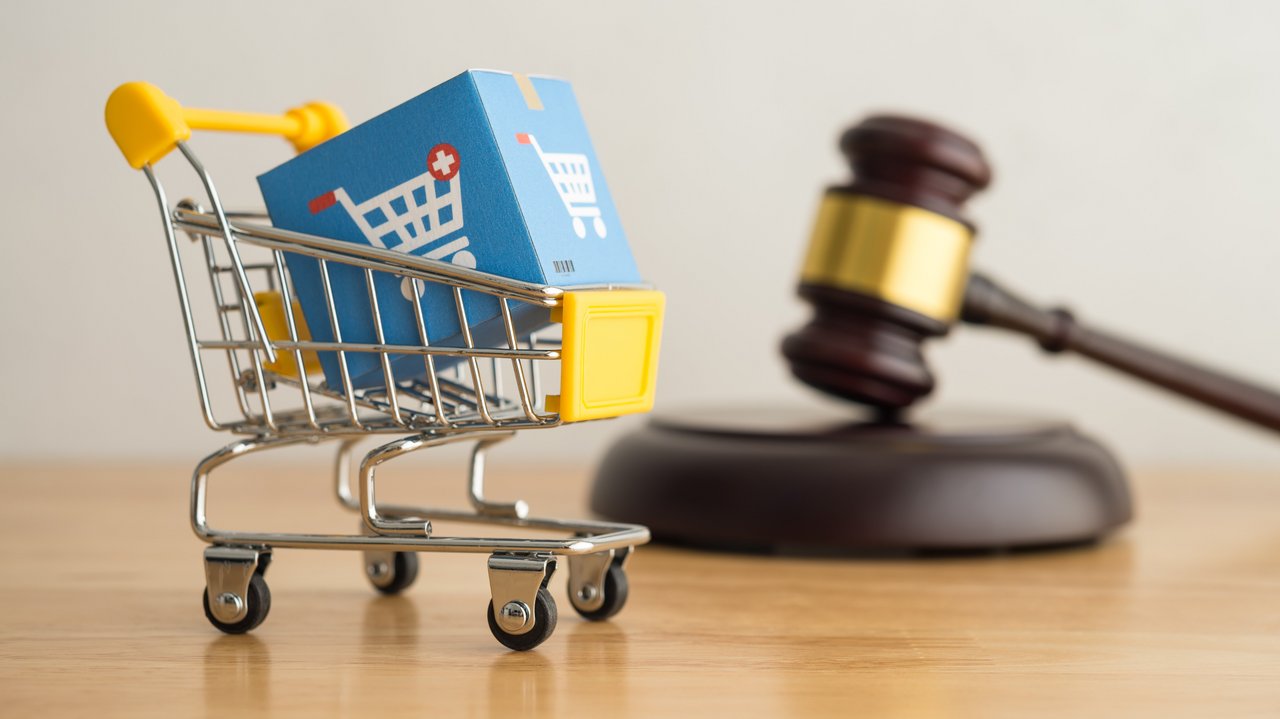 Symbolbild Online-Shopping Das Foto zeigt einen Einkaufswagen mit einer Online-Shopping-Box und einen Hammerrichter auf Holzhintergrund