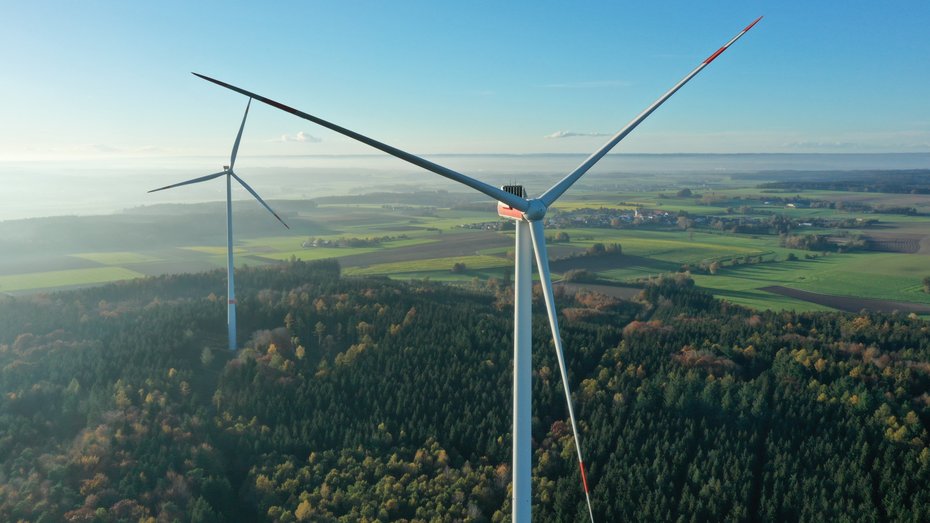 Man blickt über das Land Richtung Bodensee, im Vordergrund sind zwei Windkraftanlagen