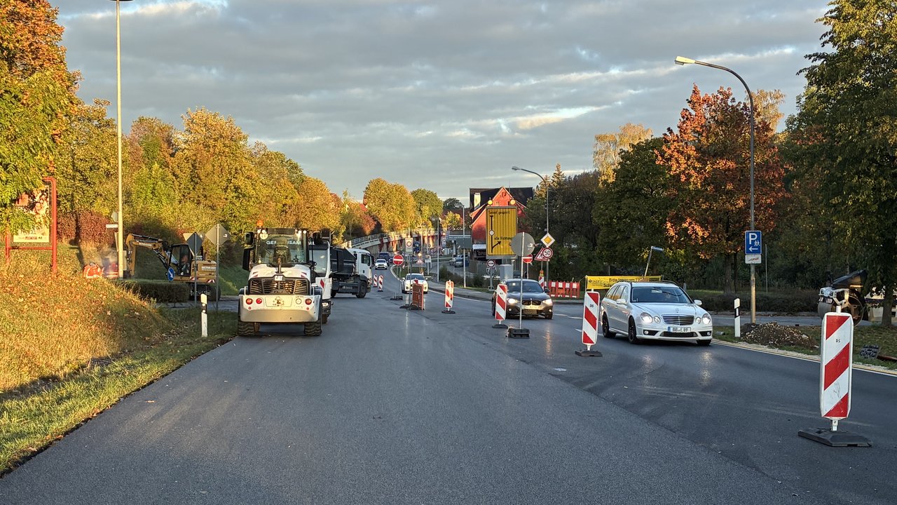 Das Foto zeigt die frisch asphaltierte Fahrbahndecke der B 463. Man sieht einige Baustellenfahrzeuge und Stehlen und einspurigen fahrenden Verkehr.