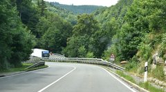 Eine Straße mit Steigung, die durch einen Wald führt.