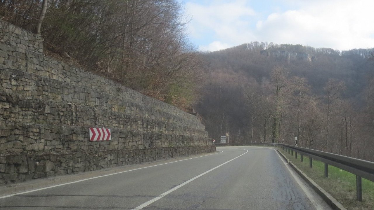 Das Foto zeigt die Holzelfinger Steige. Rechts Leitplanken und Links ein befestigter Hang und Bäume