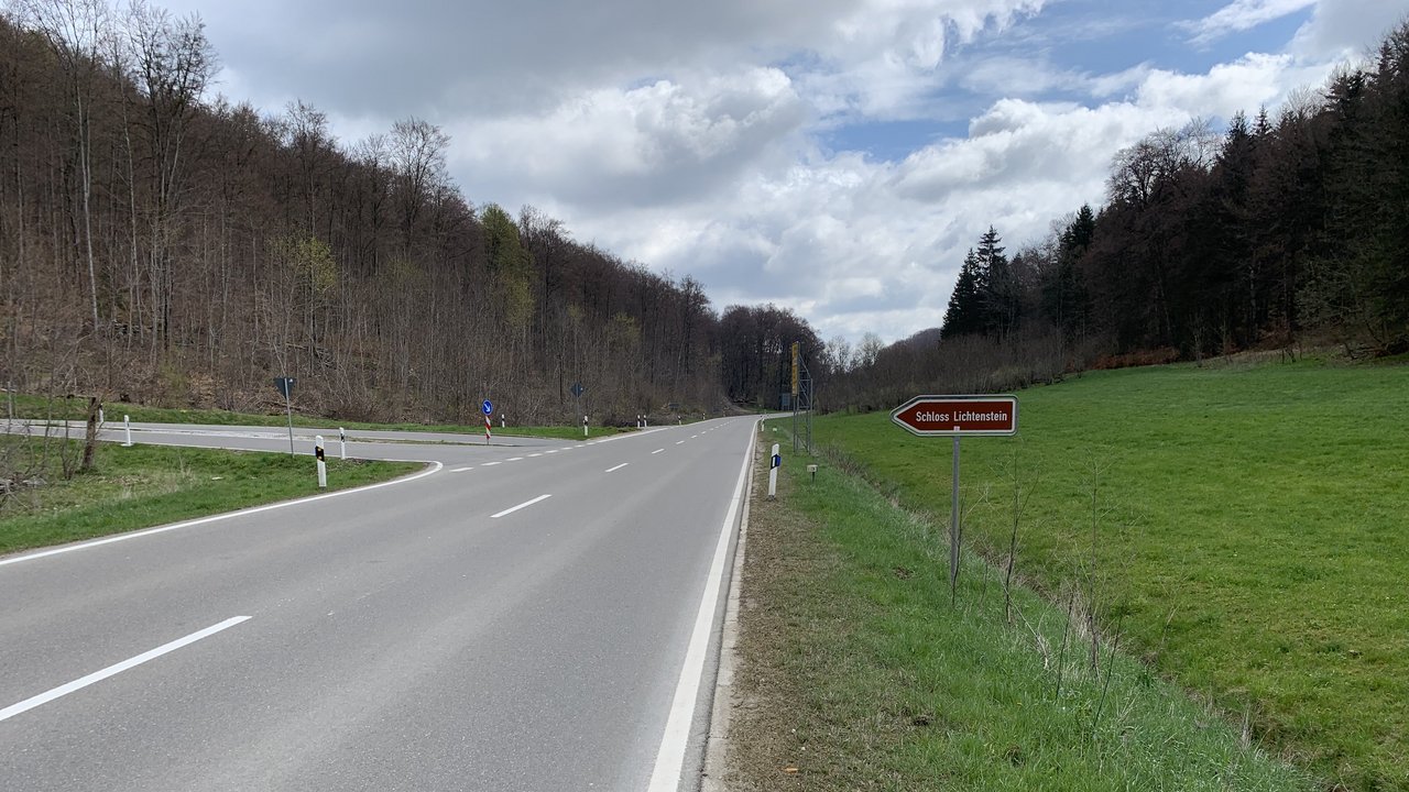 Das Foto zeigt die Abfahrt von der L 230 zum Schloss Lichtenstein; links und rechts Wiesen und Wald