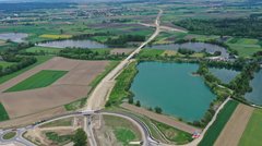Eine Luftaufnahme, auf der eine neugebaute Straße, ein See und Felder zu sehen sind.