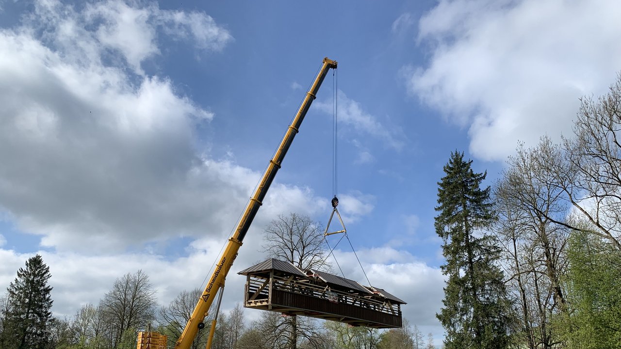 Ein sanierter Fachwerk-Brückenüberbau wird mit einem Autokran in die Höhe gezogen