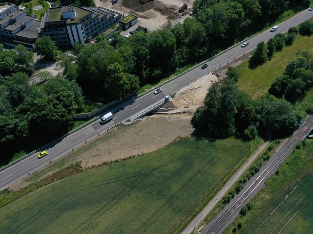 Luftbild einer Straßenbrücke über einen kleinen Bach, auf der Autos fahren