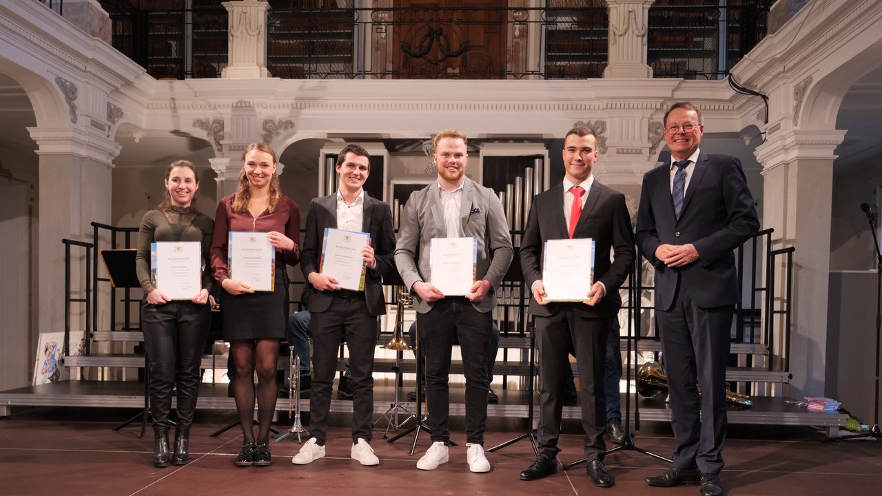 Das Foto zeigt die fünf besten Absolventinnen und Absolventen des Jahrgangs Ramona Bach, Larissa Einsiedler, Jonas Gronmaier, Martin Gronmaier, Tobias Weber und Regierungspräsident Klaus Tappeser