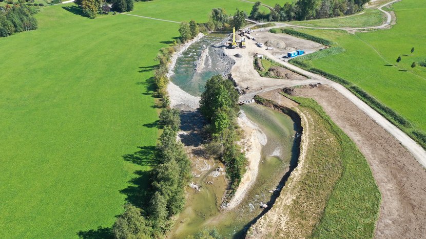 Blick von oben auf den Fluss Argen im Abschnitt 1. Man sieht den geschwungenen Verlauf mit Kiesflächen und umrahnt mit Gehölzen.