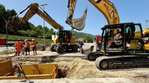 Zwei Bagger, die an einem Graben durch eine Straße arbeiten