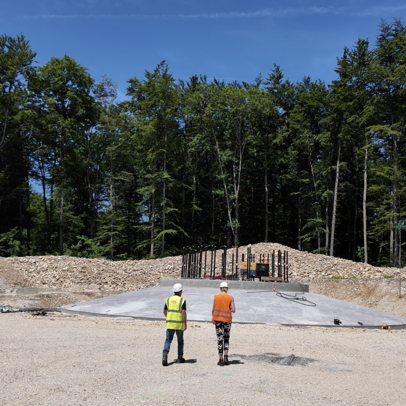 Fundament Zwei menschen, ein Mann und eine Frau, gehen auf ein kreisförmiges Fundament zu, das in seiner Form von weitem an ein Ufo erinnert.