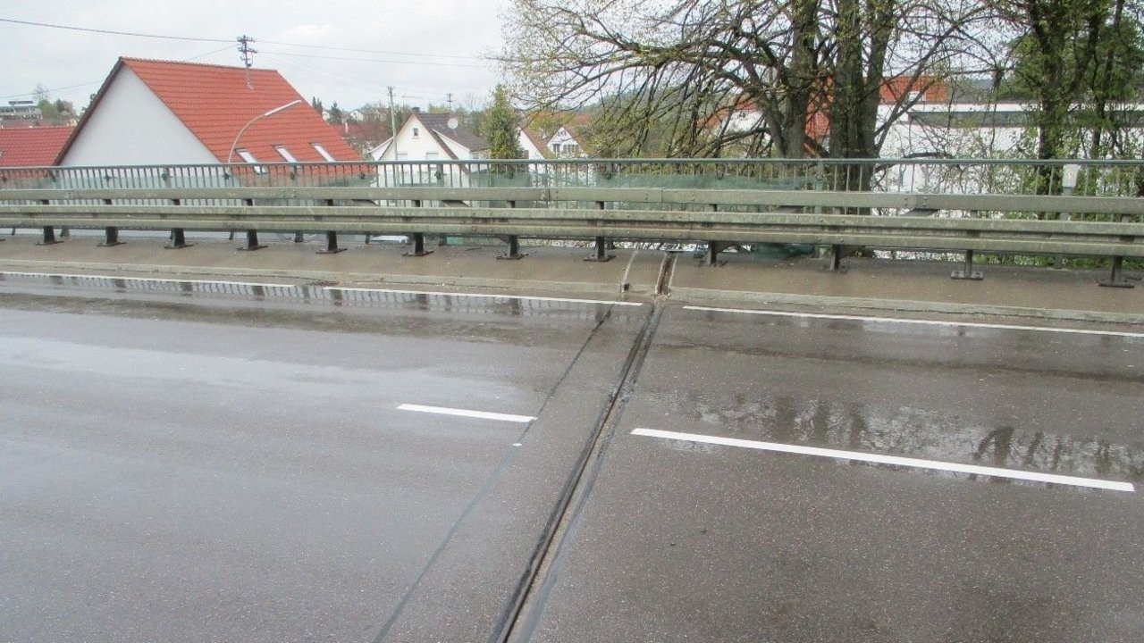 Das Bild zeigt die Übergangskonstruktion der Lochenbachbrücke bei Balingen-Weilstetten in Fahrtrichtung Albstadt; im Hintergrund sieht man das Brückengeländer und mehrere Häuser