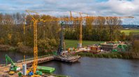 Zwei Kräne und eine Pfahlramme an einer Brückenbaustelle