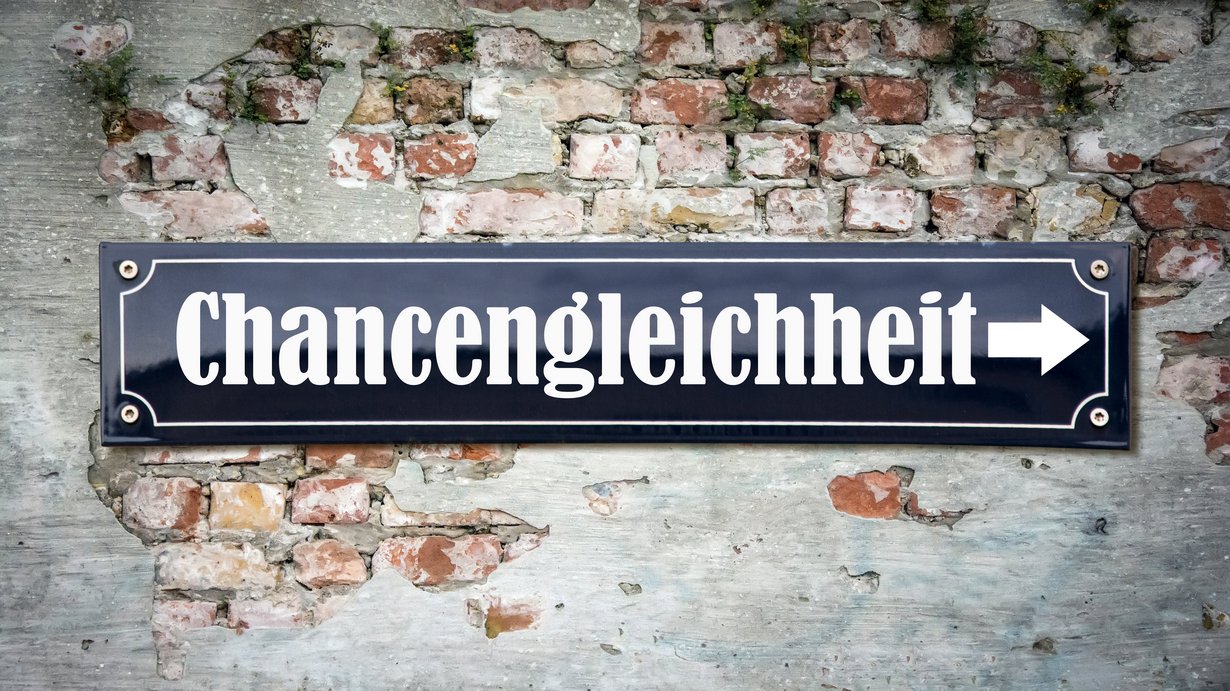 Schild mit Aufsicht "Chanchengleicheit" angebracht an einer alten Backsteinwand, wo der weiße Putz stellenweise abgegangen ist und die Backsteine zu sehen sind