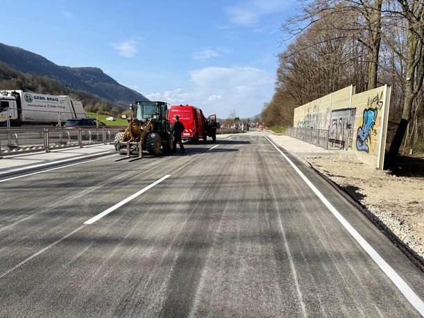 Foto einer Straße, auf der kein Verkehr fließt. Der Straßenbelag und die Markeirungen sind neu, es befinden sich noch Baufahrzeuge auf der Straße.
