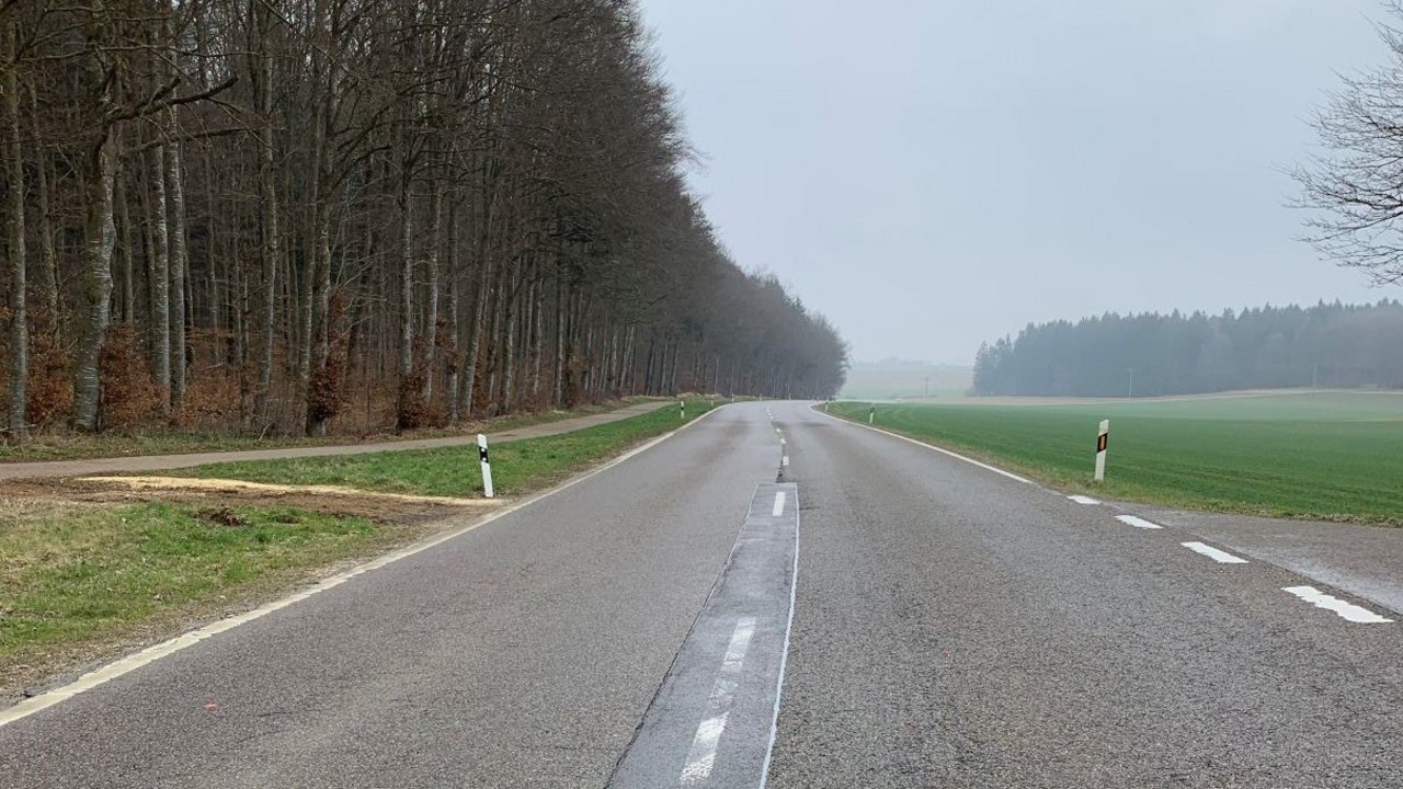 Das Foto zeigt die B 28 zwischen Feldstetten und Blaubeuren. Link ein Waldstück und ein Forstweg und rechts Felder und Wiesen. Im Hintergrund Wälder
